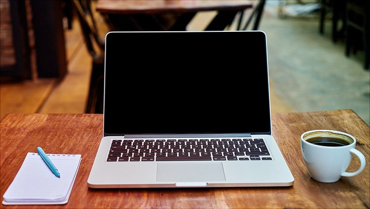 Laptop mit Kaffee und Notizblock