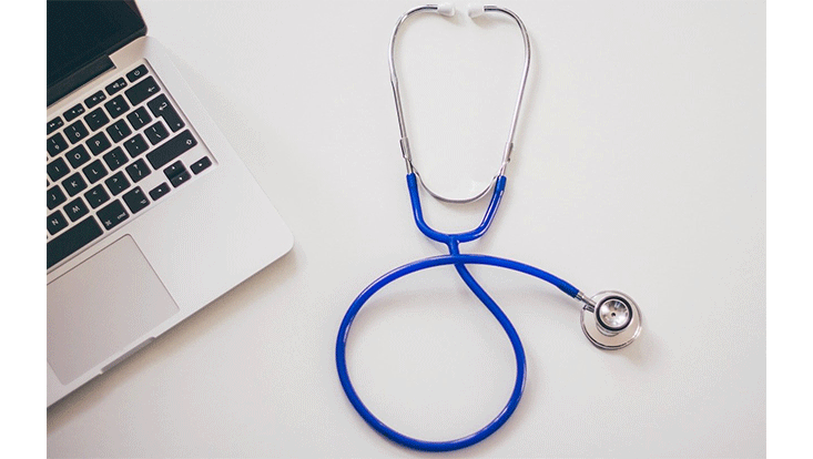 Blaues Stethoskop und Laptop auf einem Tisch