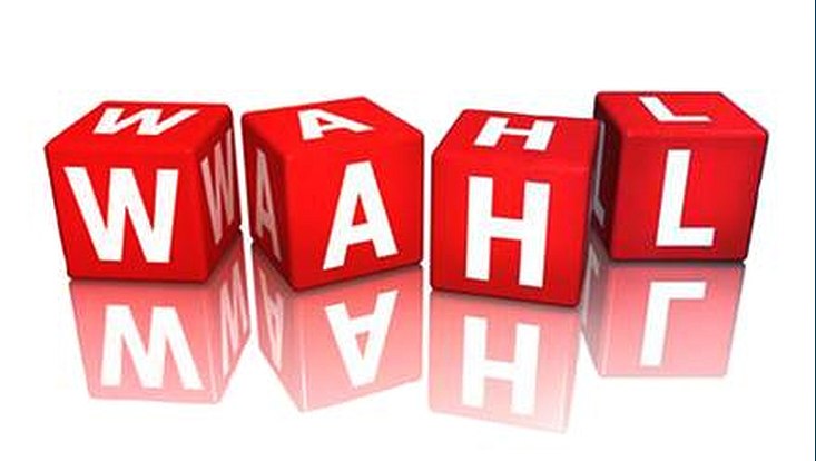 Rote Würfel, auf denen in weißer Schrift "Wahl" steht. Die Würfel spiegeln sich im weißen Boden