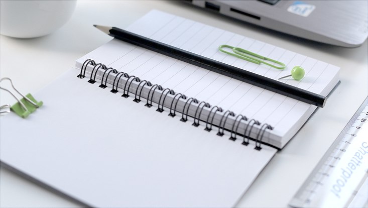 Schreibtisch mit Ringbuch und Bleistift