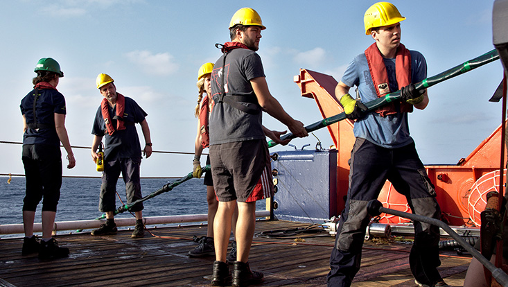 Forschende mit Sicherheitsuntensilien auf einem Schiff