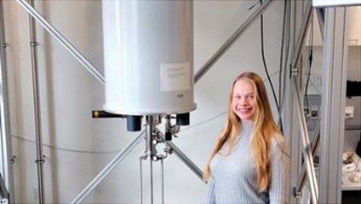 Photograph of Jana Meyer in front of the Triton cryostat