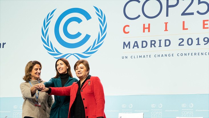 Drei Frauen legen auf der Bühne der UN-Weltklimakonferenz COP25 in Madrid ihre Hände aufeinander