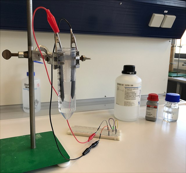 Stativ mit Falcon Tube und Kabelklemmen sowie Reagenzien für den Aufbau und Versuch des Lithiumionenakkumulators.