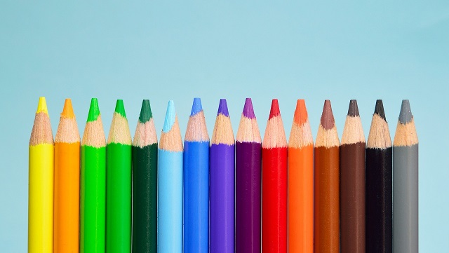 Buntstifte stehen nebeneinander vor blauem Grund.