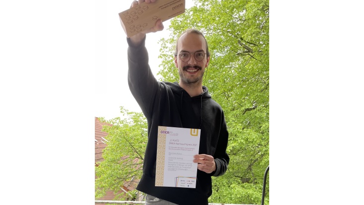 Max hält DMAE Trophäe in die Kamera.