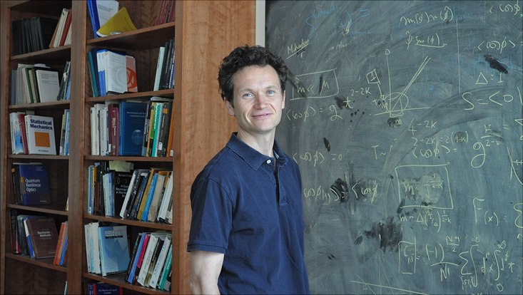 Eugene Demler vor Bücherwand und Tafel