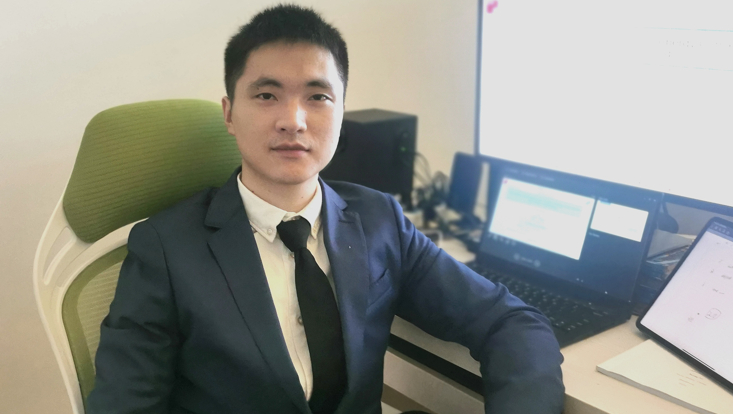 Song Li successfully defended his doctoral thesis. The picture shows Song Li at a desk with computers.