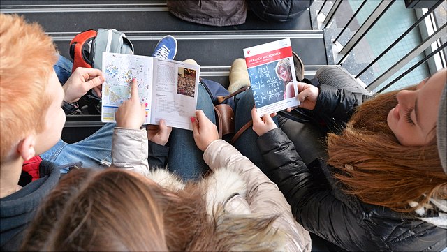 3 Studierende lesen die Wilkommensbroschüre der Universität Hamburg.