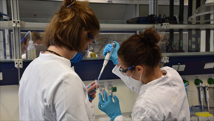 two girls in white lab coats experimenting