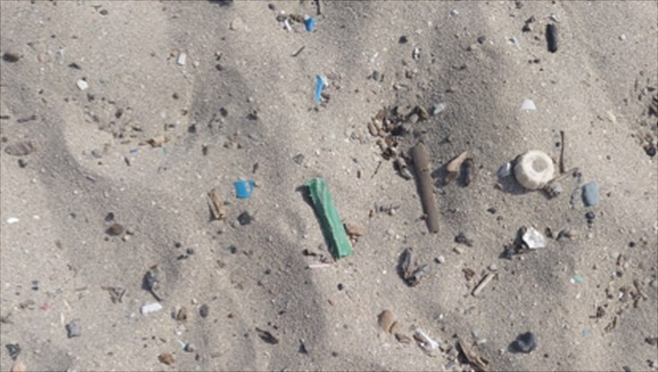 Müll und Plastikteile im Sand.