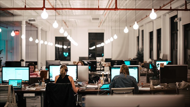 large joint workspace with people sitting side by side working on laptops