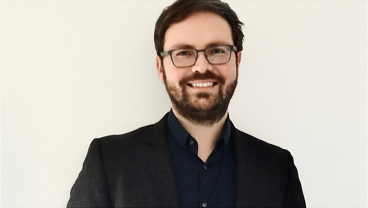 Portrait eines lachenden Mannes mit dunklen Haaren, Bart und Brille