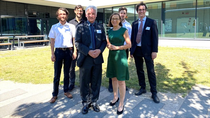 gruppenbild-besuch-gümbel-733x414 Five men and a women in front of a research building.