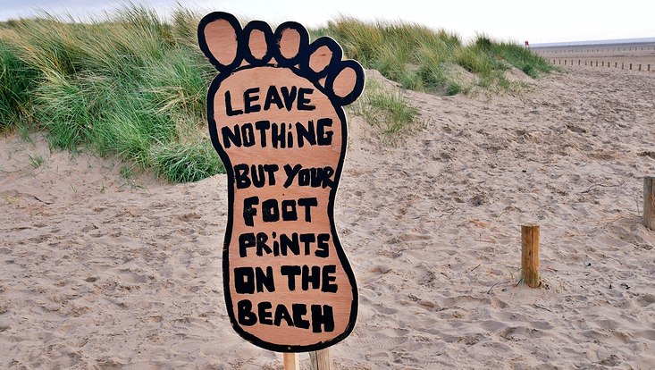 Sign on the beach stating "Leave nothing but your footprint on the beach"