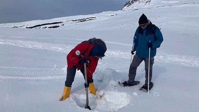 Two scientist showeling through the snow