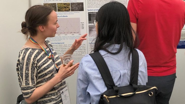 Scientists discussing in front of a scientific poster