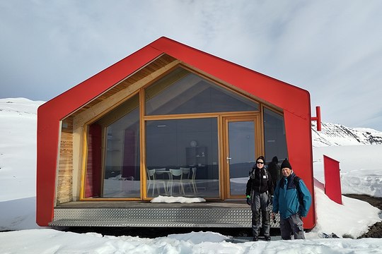 two scientists in front of the red hut