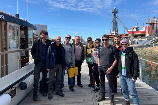 a group of scientists standing at the harbour of Ilulissat at a sunny day