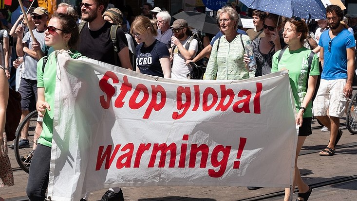 Demonstrators of the Last Generation holding a white banner with the red inscription "Stop global warming!".