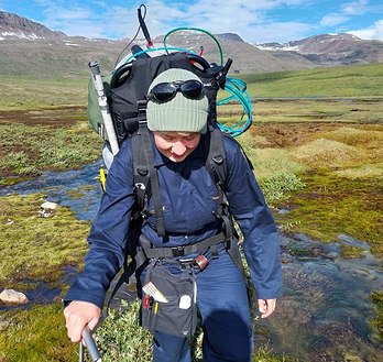 Scientist backpacking gas flux analyzer in the arctic tundra