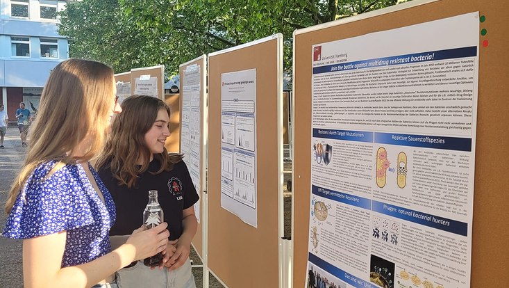 zwei Studentinnen betrachten ein wissenschaftliches Poster