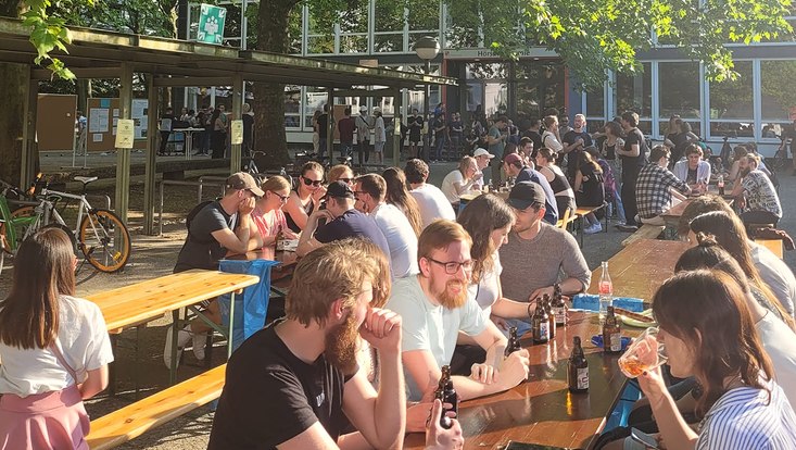 Menschen sitzen an Bierzeltgarnituren