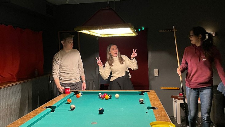 drei Studierende am Billiard spielen