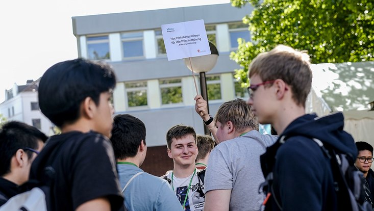 -dsf0696-733x414 Schüler mit einem Schild in der Hand, darauf steht: Hochleistungsrechnen für die Klimaforschung.