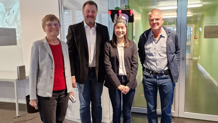 Ge Cheng und Panel mit Doktorhut nach der erfolgreichen Verteidigung