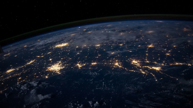 The world from above. It is dark, you can see all the lights of the earth.
