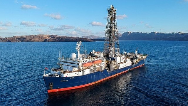 Das Bild zeigt die die JOIDES Resolution innerhalb der Santorini Caldera. Die Expedition 398 hat erstmals den Meeresboden rund um die griechischen Vulkaninseln mit einem Forschungs-Bohrschiff untersucht.