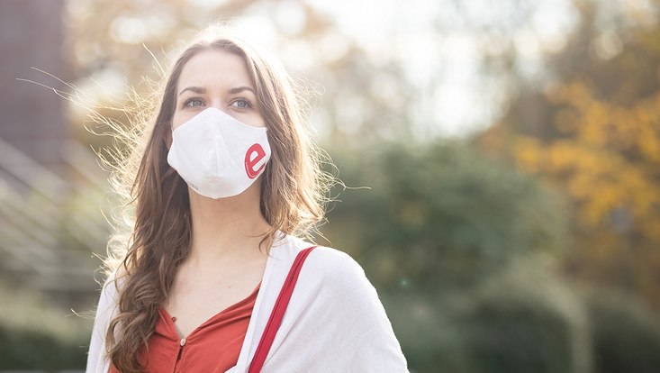 Junge Frau mit Stoffmaske der Exzellenz-Universität Hamburg