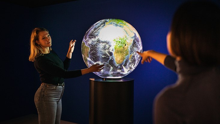 Two young women around a glowing globe.