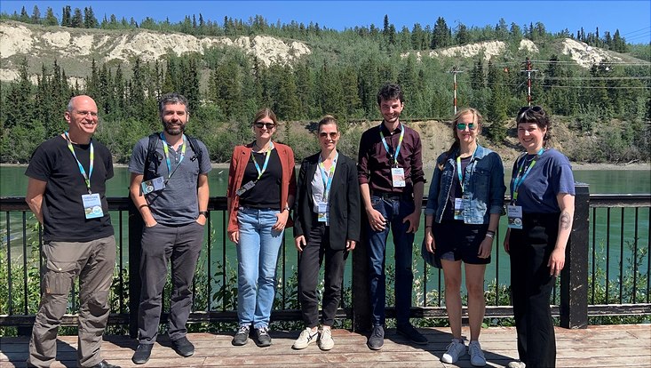 Group picture of seven researchers on a terrrace in front of a river and mountains