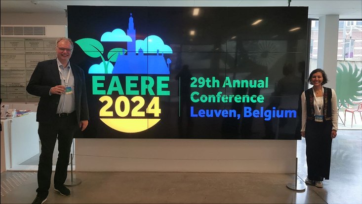 Hermann and Emily in front of the EAERE logo
