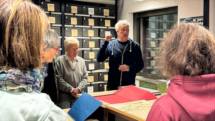 Der Oberkustos des Herbarium Hamburgense, Dr. Matthias Schulz, zwischen den Ragalreihen des Herbariums mit einer GRuppe von Teilnehmdenden
