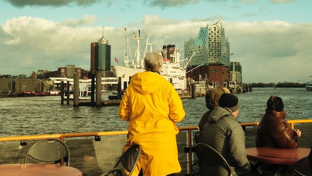 Frau im Regenmantel blickt auf die Elbphilharmonie