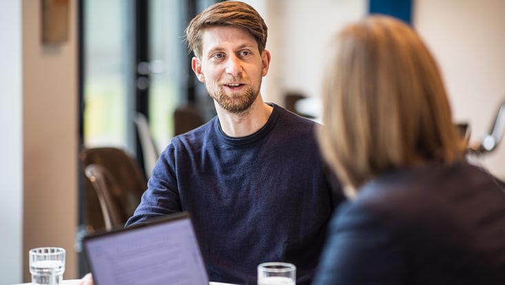contact-symbolbild-c-cuhh-esfandiari-733x414 junger mann sitzt einer frau mit laptop gegenüber
