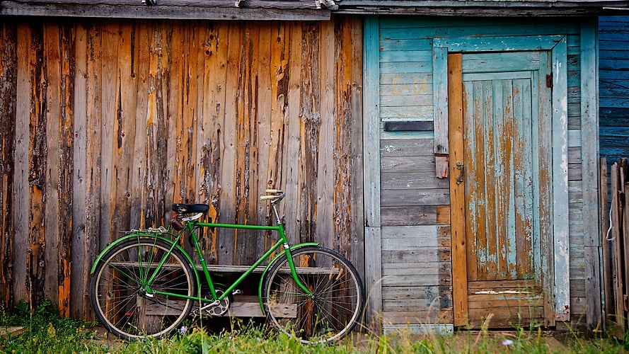 green man's bicycle leaning against old wooden shed