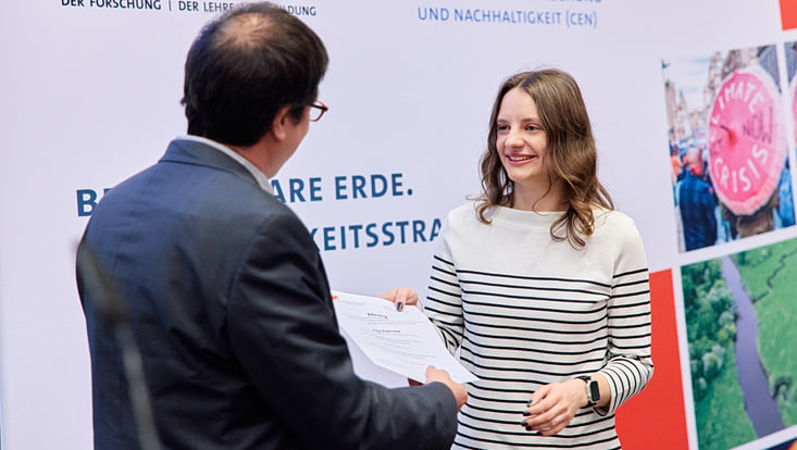 2025-02-cen-graduiertenfeier--7178-733x414 Prof. Felix Ament übergibt einer Master-Absolventin ihre Urkunde.