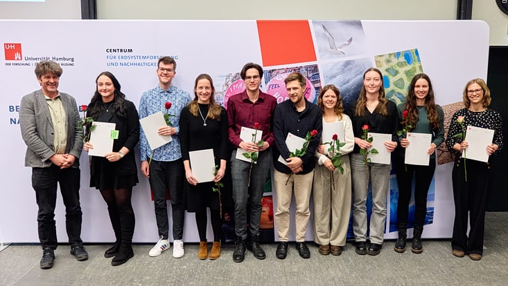 2025-02-cen-graduiertenfeier--7440-733x414 Prof. Lars Kutzbach mit neun Master-Absolvent:innen, die jeweils ihre Urkunde und eine Rose in den Händen halten.