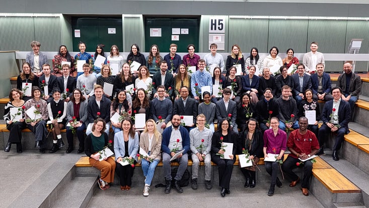 2025-02-cen-graduiertenfeier--8348-733x414 Gruppenbild der Graduierten mit ihren Urkunden und Rosen.