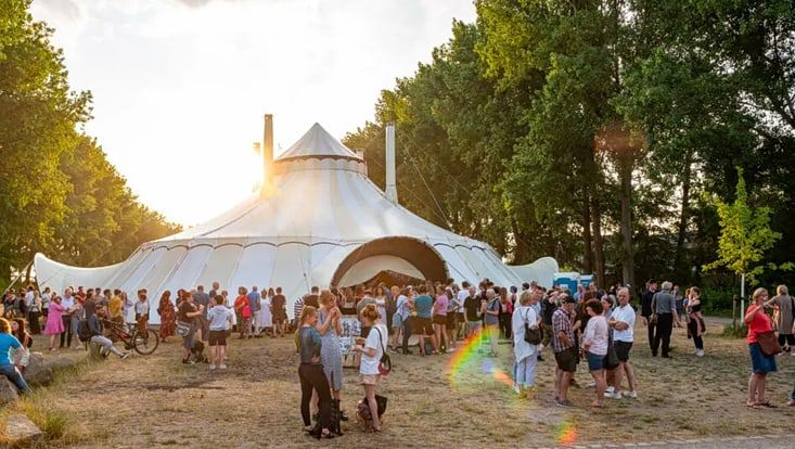 zartinka-zelt-außenansicht-733x414 Außenansicht des Zirkuszelt Zartinka. Ein weißes Zelt auf einer ins Sonnenlicht getauchten Wiese