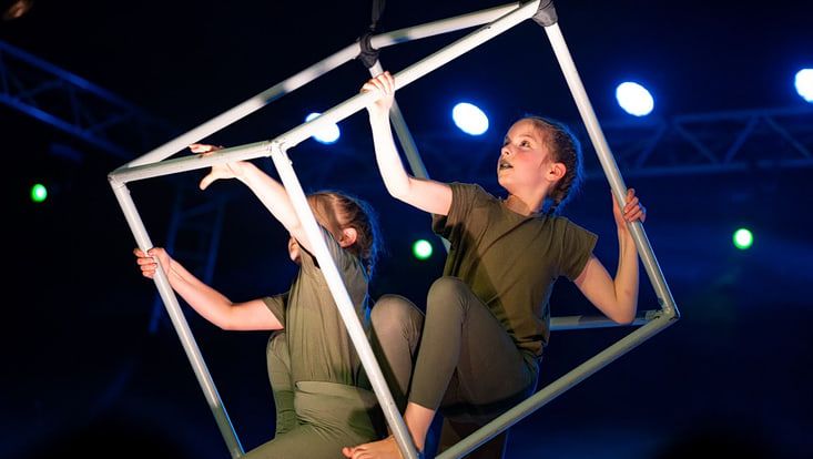 zwei Kinder in einem Artistik-Würfel vor schwarzem Hintergrund während einer Zirkusshow des Zirkus Zartinka