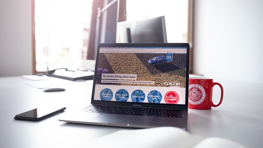 Work place with laptop and open browser on UHH homepage and UHH mug