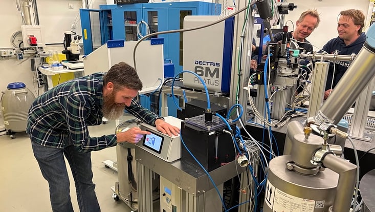Men in front of a reseaqrch instrument.