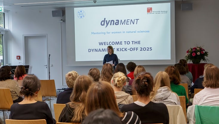 co-2171-733x414 A woman stands in front of a screen in a seminar room.