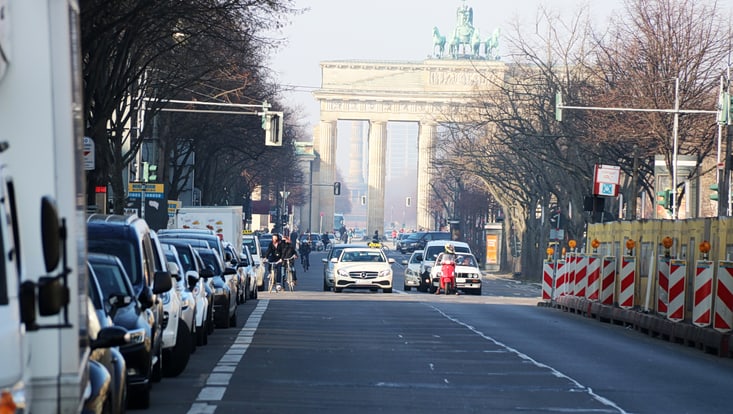 Berlin, befahrene Straße in der Stadt, im Hintergrund das Brandenburger Tor zu sehen