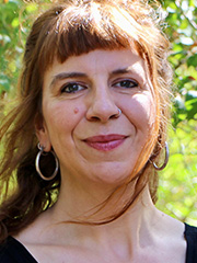 Portraitfoto von Anna Fünfgeld. Sie hat rote Haare die sie offen mit einem Pony trägt. Sie lächelt.